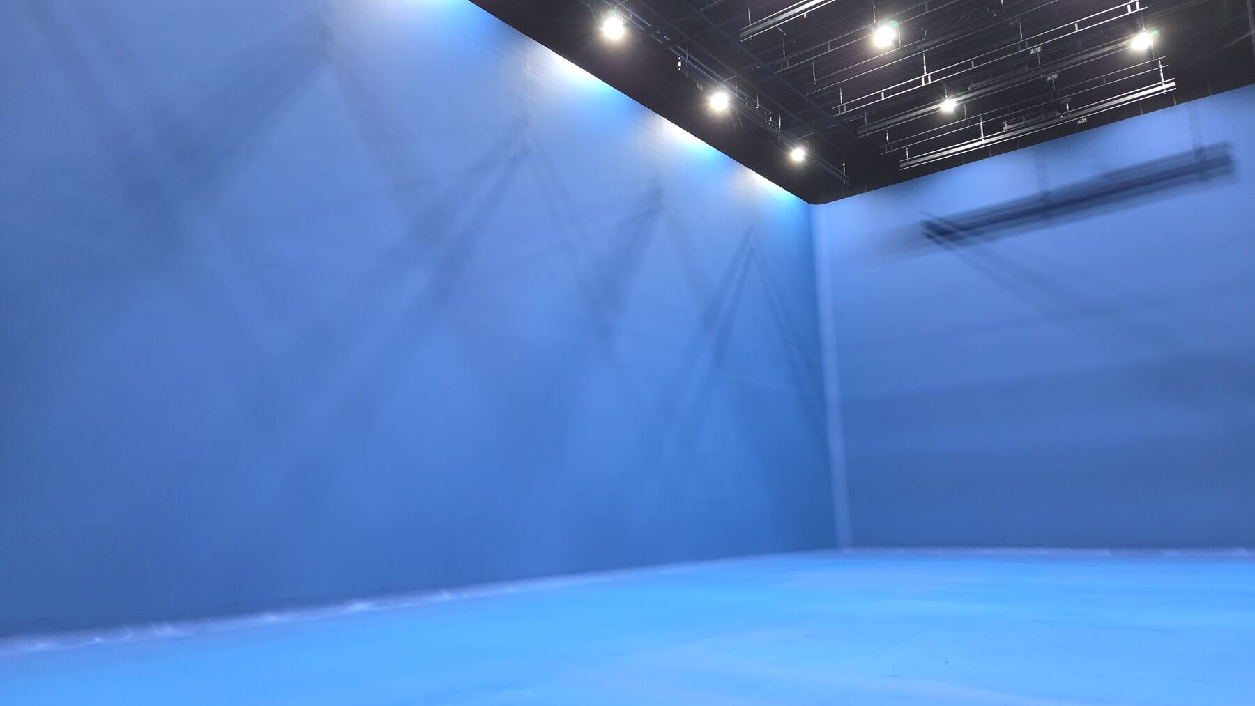 Wide blue-screen stage with crew preparing a shoot