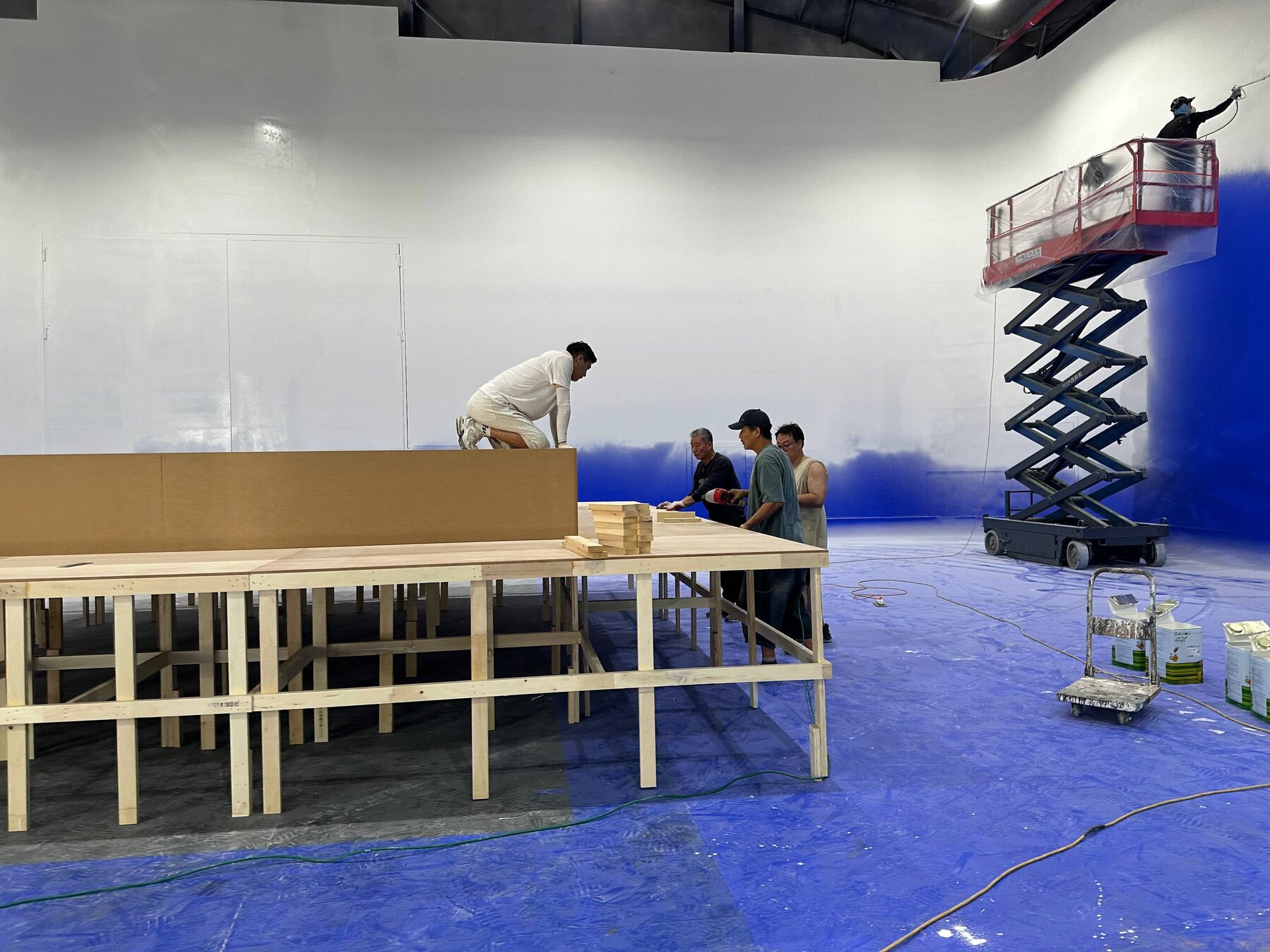 Crew framing a wooden platform riser on a cyclorama stage floor