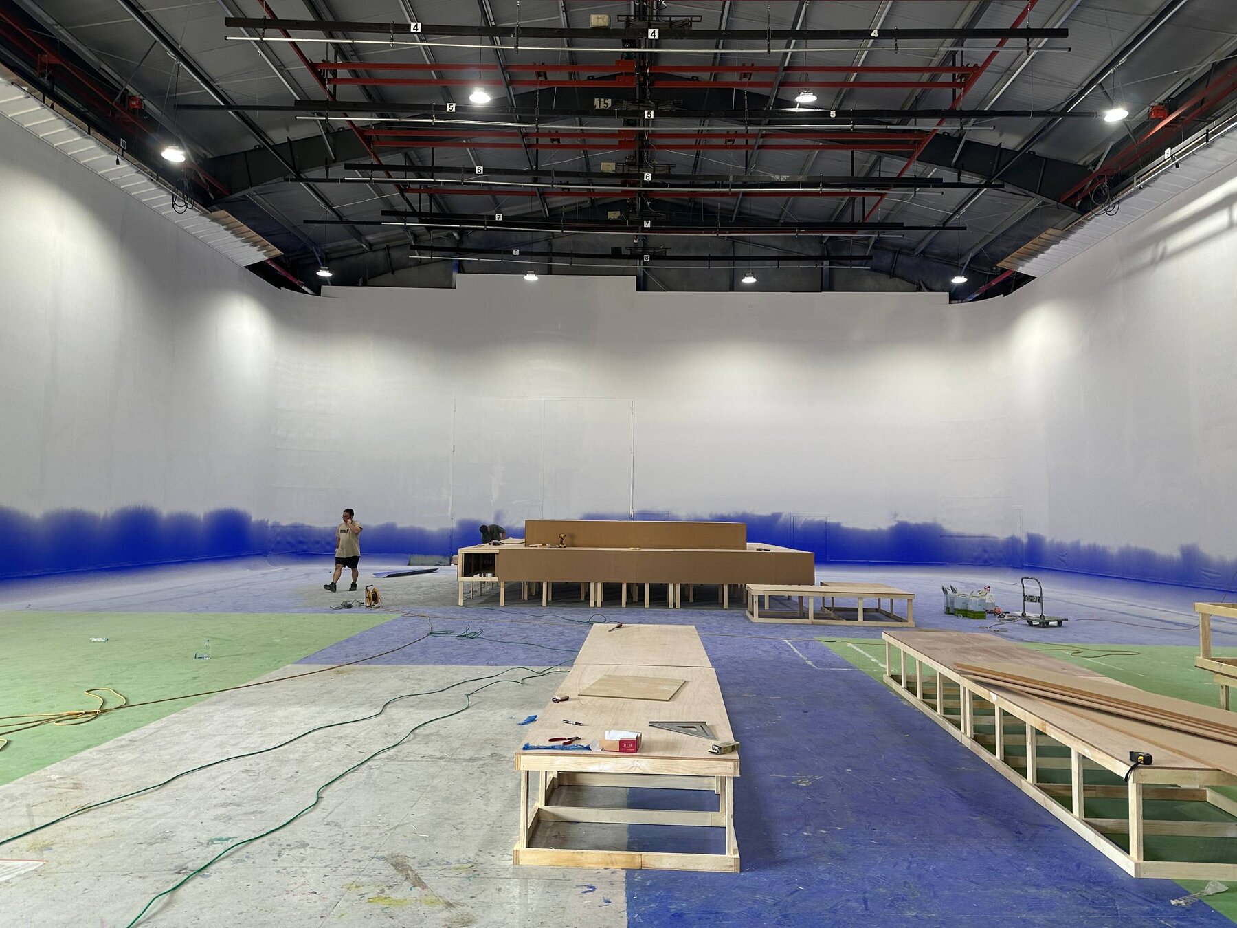 Wooden platform risers laid out across the cyclorama floor