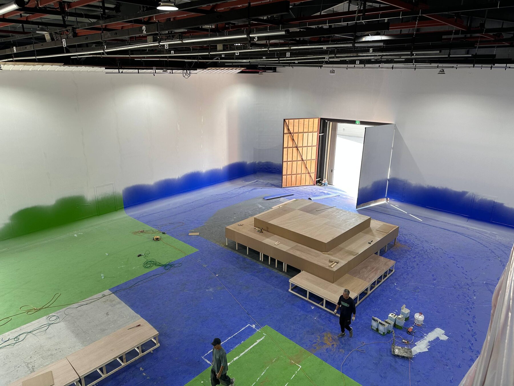 Unpainted wooden stair pyramid fully formed on the white cyclorama floor